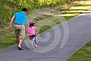 Father teaching daughter to ride her bicycle