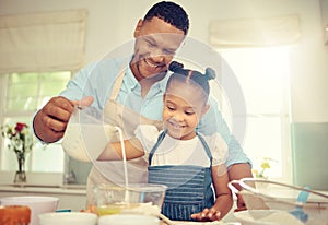 Father teaching girl to bake and make dough in a messy kitchen. Caring parent and little daughter baking together in