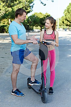 Father teaching girl to ride kick scooter