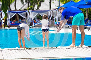 Father teaching his daughters to dive in pool on