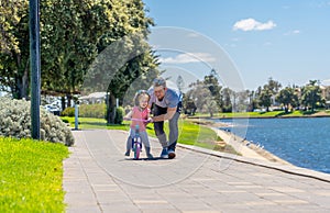 Father teaching his little daughter to ride a bike and having fun together at the park