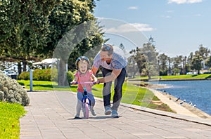 Father teaching his little daughter to ride a bike and having fun together at the park