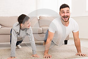 Father teaching his son doing push-ups exercises