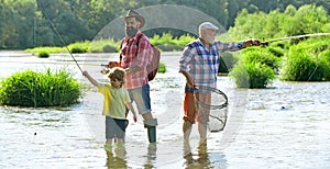 Father teaching his son fishing against view of river and landscape. Happy weekend concept. 3 men fishing on river in