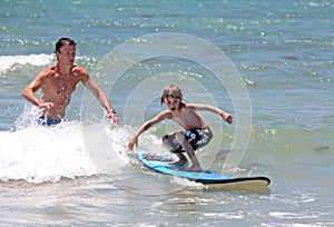 Father teaching his young son how to surf