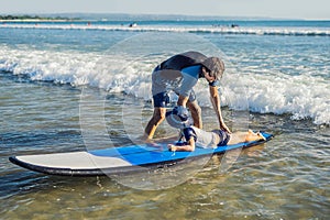 Father teaching his young son how to surf in the sea on vacation