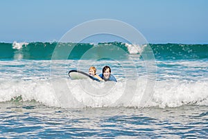 Father teaching his young son how to surf in the sea on vacation