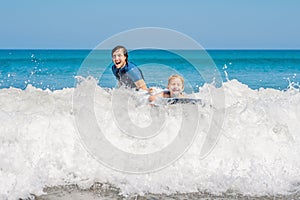 Father teaching his young son how to surf in the sea on vacation