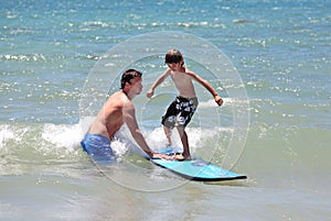 Ensenando su joven un hijo sobre el surfear 