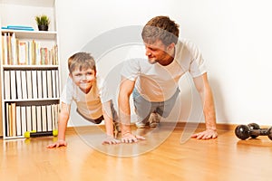 Father teaching kid son doing push-ups exercises