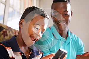 Father Teaching Mobile Telephone Technology To Son At Home