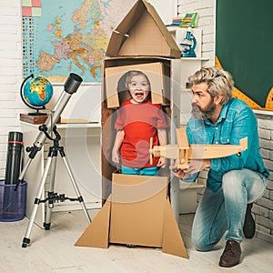 Father teaching son. Child in astronauts costumes with toy rocket playing and dreaming of becoming a spacemen. Astronomy