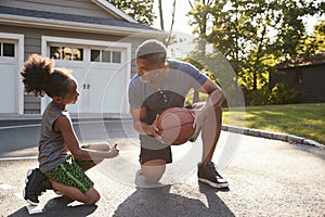 Father Teaching Son How To Play Basketball On Driveway At Home