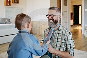 Father teaching son how to tie a tie. Memorable moment for young boy.