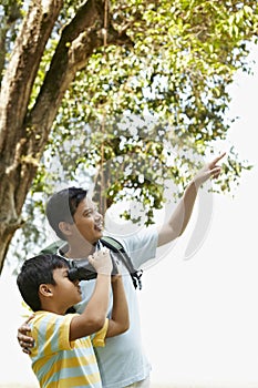 Father teaching son how to use binoculars. Conceptual image