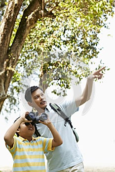 Father teaching son how to use binoculars. Conceptual image