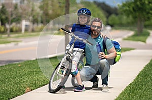 Father teaching son riding bike. Happy loving family. Father and son hugging. Child in bike helmet learning to ride