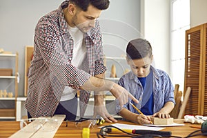 Father teaching son to build toy house at home carpentry and joinery workshop
