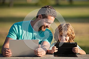 Father teaching son to use laptop, dad and school boy child looking computer screen and tablet, playing game, watching