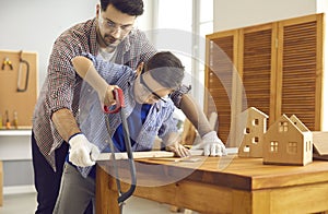 Father teaching son use sharp handsaw for woodworking at home carpentry workshop