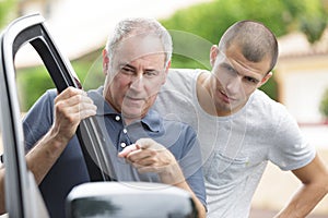 father teaching teenage son about car photo