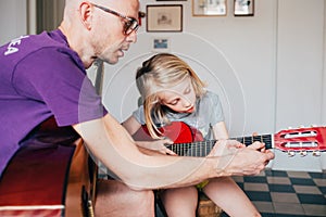 Father teaching to his daughter how to play guitar