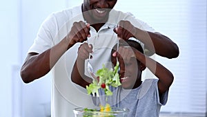 A father teaching to his son how to mix salad