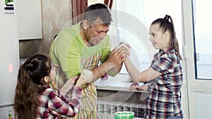 Father teases little daughters powdering noses with flour