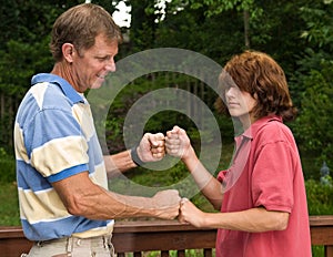 Father and teen son fist-bumping