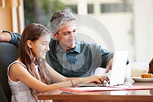 Father And Teenage Daughter Looking At Laptop Together photo