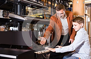 Father and teenage son examining keyboards in guitar shop