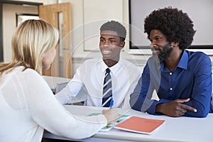 Father And Teenage Son Having Discussion With Female Teacher At High School Parents Evening