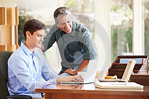 Father And Teenage Son Looking At Laptop Together