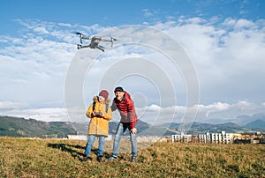 Father and Teenager boy son dressed yellow jacket piloting a modern digital drone using remote controller. Modern technology