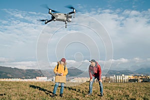 Father and Teenager boy son dressed yellow jacket piloting a modern digital drone using remote controller. Modern technology