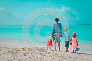Father with three kids play on beach, family at sea