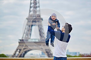Father throwing his little son in the air near the Eiffel tower