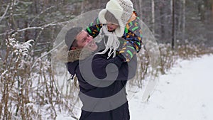 Father throwing son in air, slow motion. Father and son having fun in a winter park, father throwing young boy up into