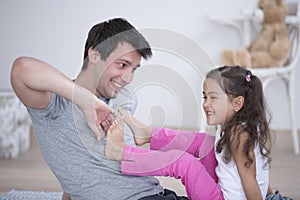 Father tickling daughter's foot at home