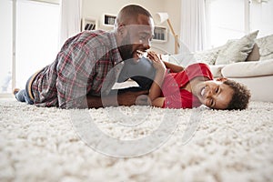 Father Tickling Son As They Play Game In Lounge Together