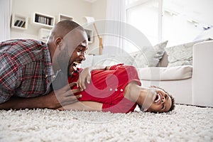 Father Tickling Son As They Play Game In Lounge Together