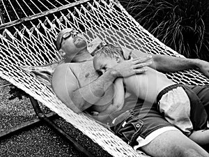 Father and toddler son laying on hammock.