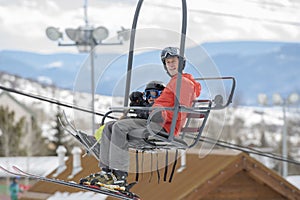 Father & Toddler Son On a Ski Lift with the Snowy Colorado Mountain Resort in the Background