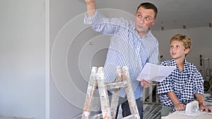 Father together with little son checking blueprints before renovating a room