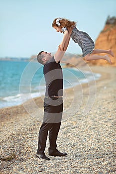 Father toss up daughter playing together on the beach carefree h