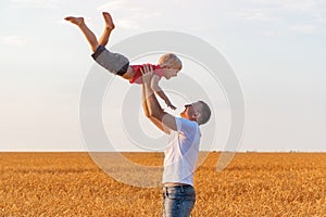Father tosses child boy high into sky. Dad and son having fun on outdoors photo