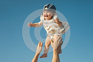 Father tossing baby in the air, summer time concept.