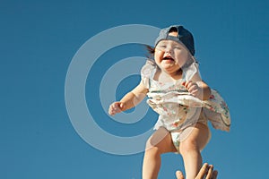 Father tossing up his little daughter in the air. In sunny day