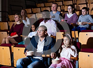 Father and tween daughter watching film together in cinema