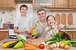 Father and two children in home kitchen interior. Happy family, girl and boy having fun with fruits and vegetables. Healthy food c